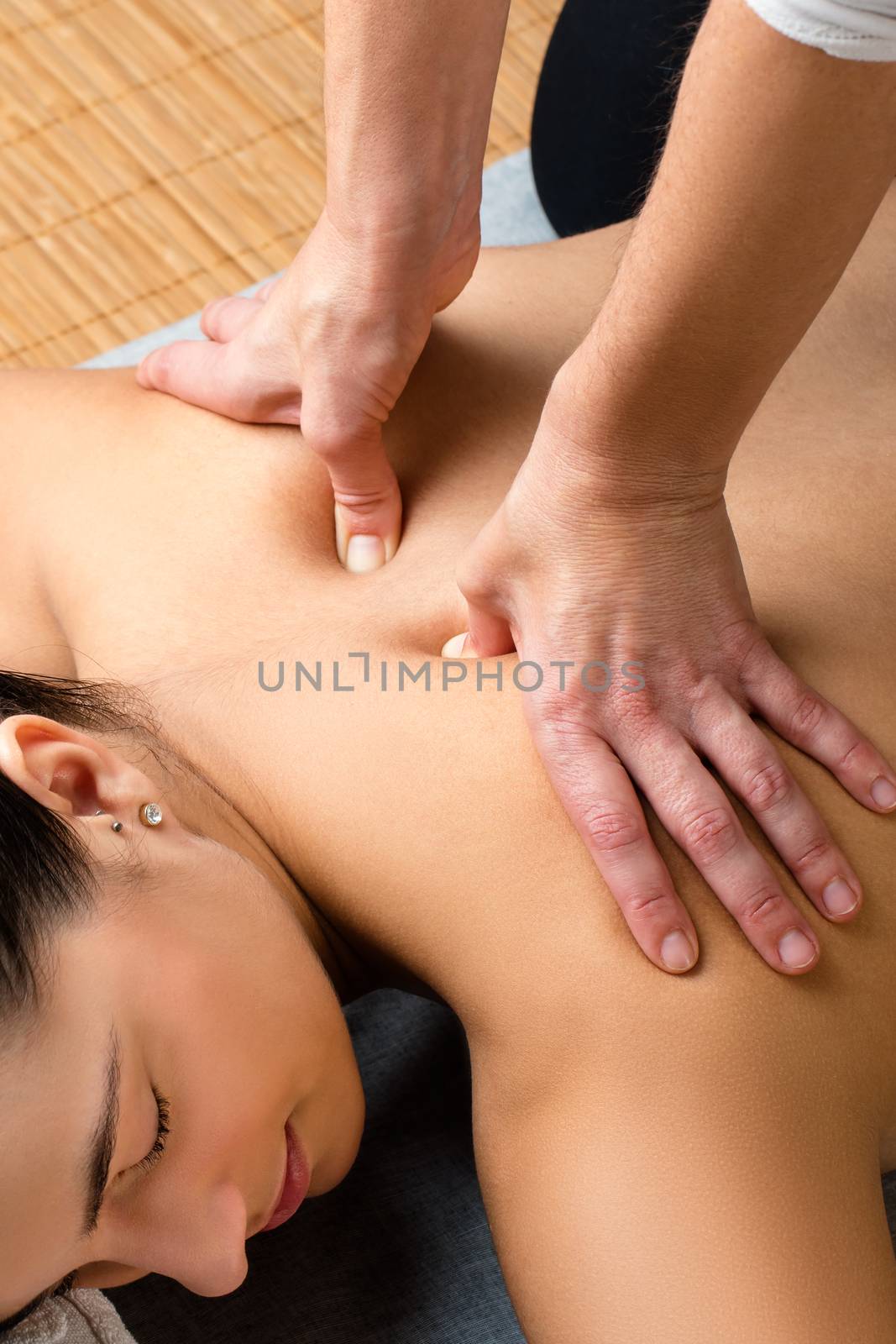 Close up of woman having kinesiological back treatment.Hands applying pressure with thumbs on spinal column.