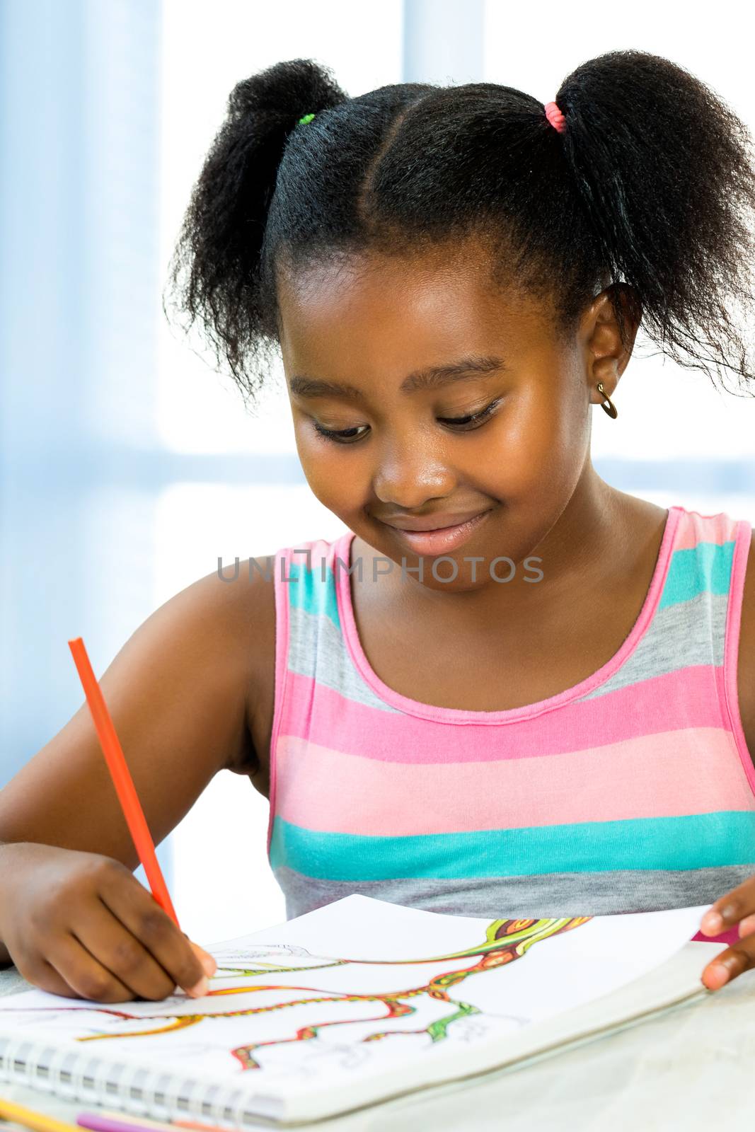 Close up portrait of creative little african girl drawing at desk.Kid creating colorful drawing with color pencils.