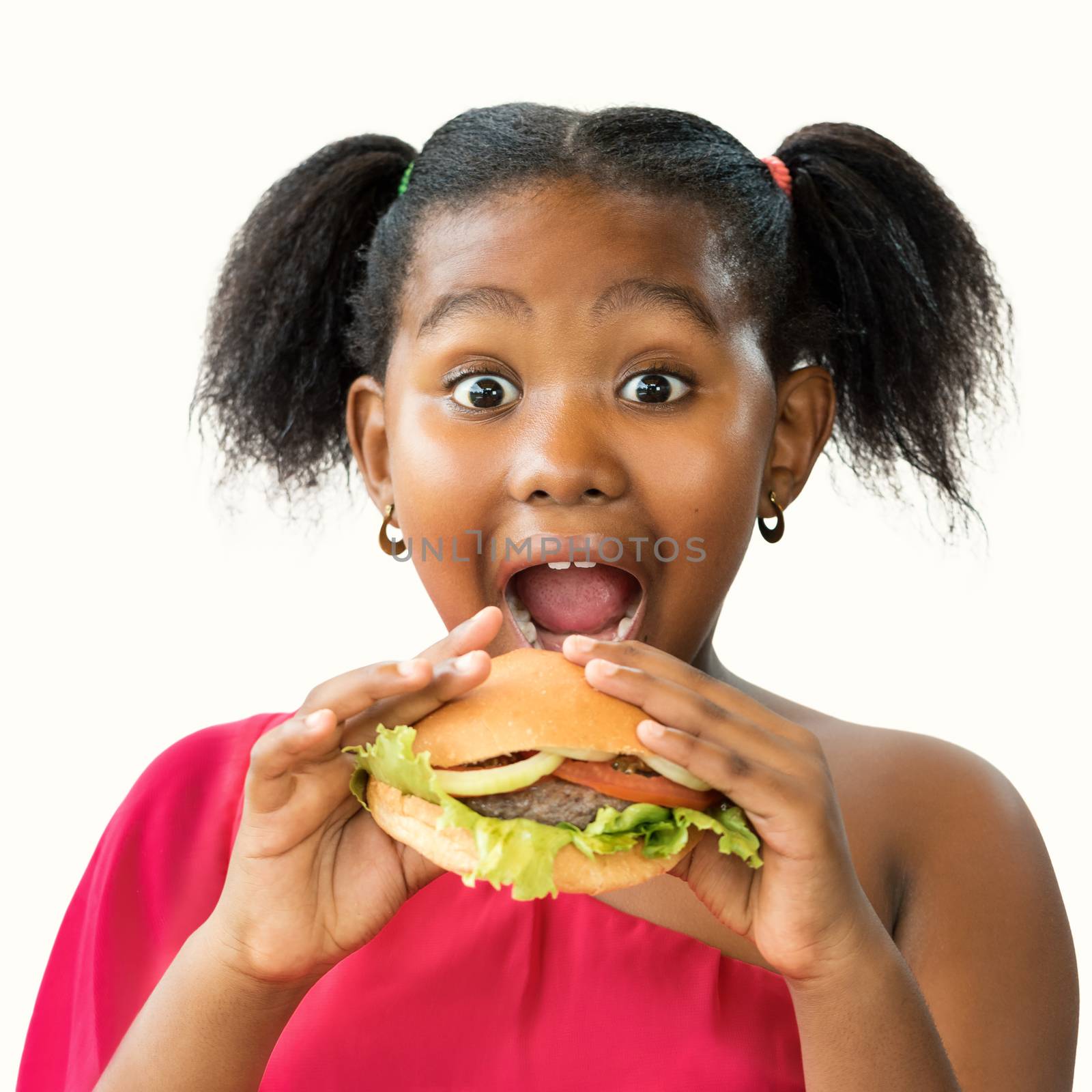 Close up face shot of expressive little african girl with open mouth and big eyes about to eat hamburger.Kid holding meat hamburger infant of face isolated on white background.