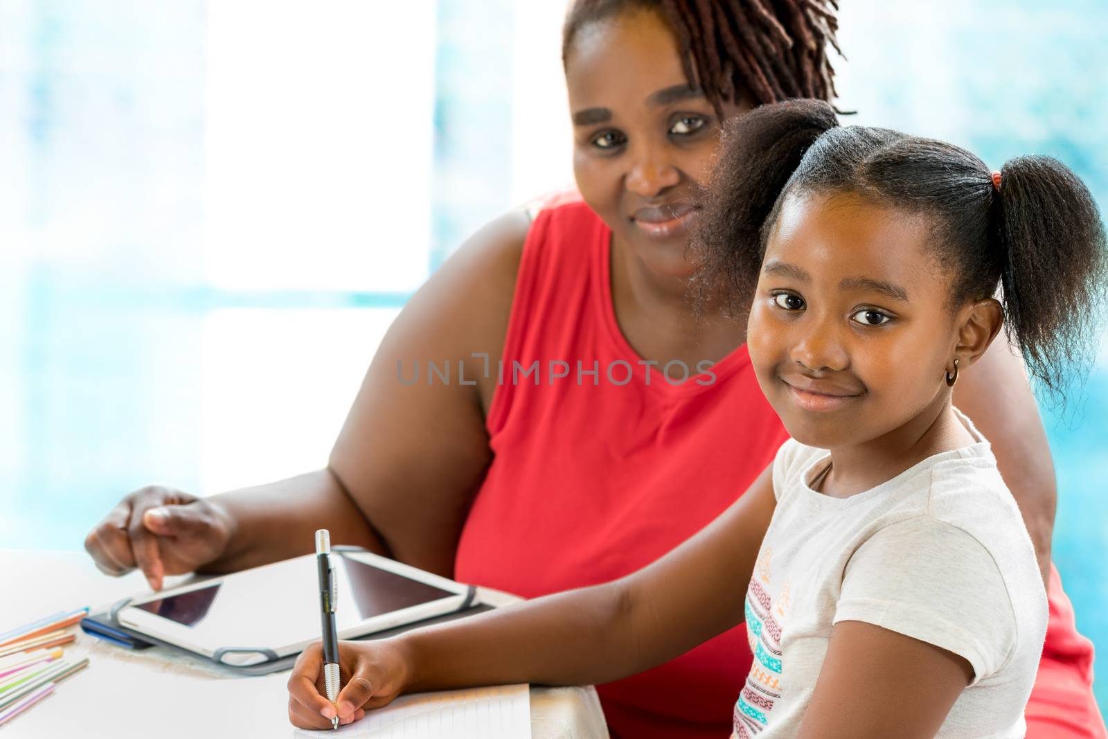 Little african student doing home work with mother. by karelnoppe