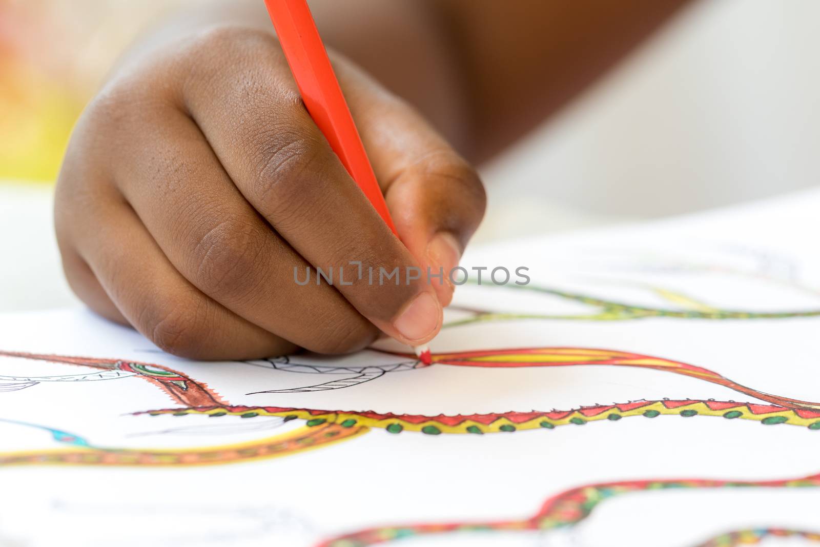 Macro close up detail of african hand drawing on paper.Child creating colorful art work with pencils.