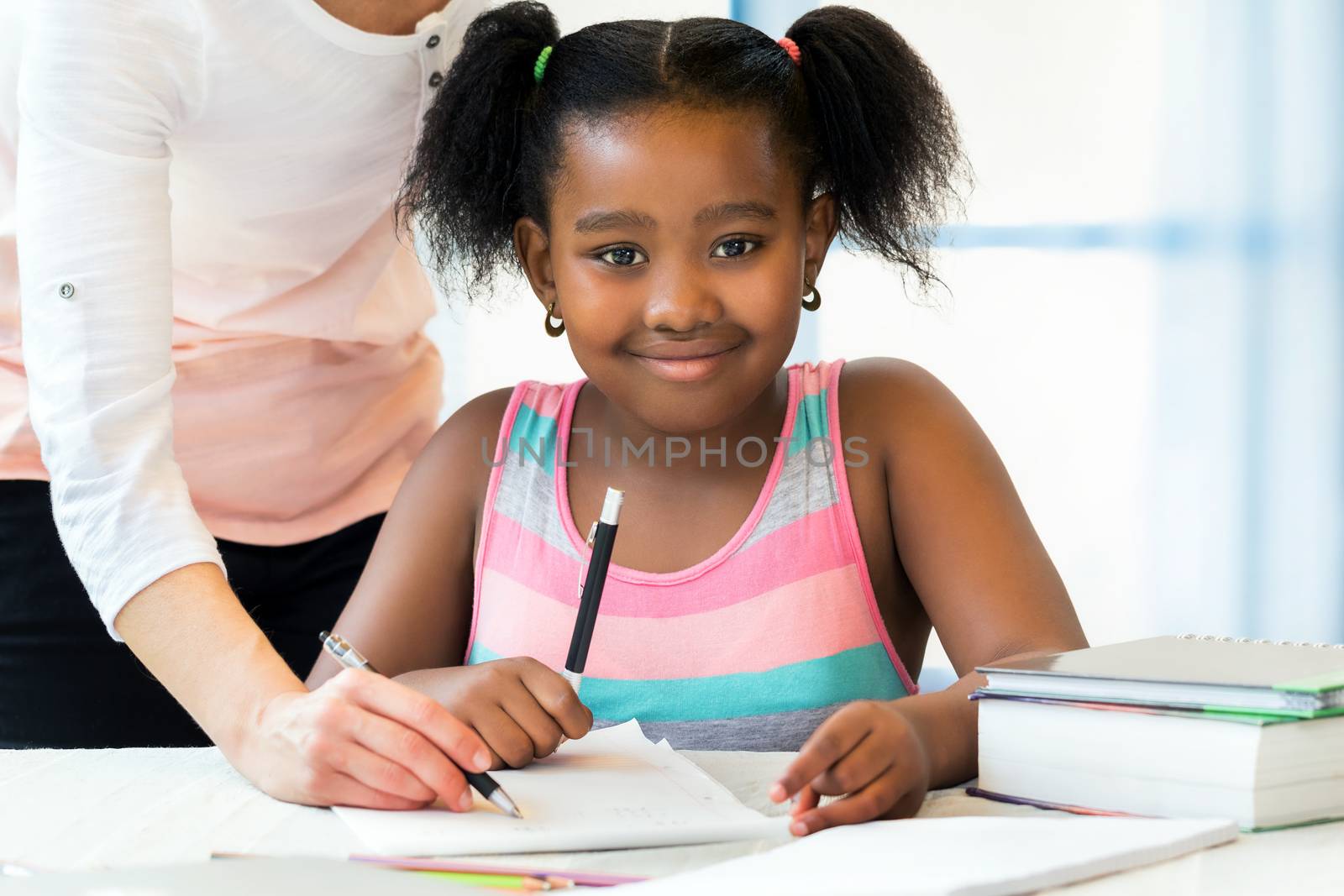 Portrait of cute little african student doing homework with cauc by karelnoppe