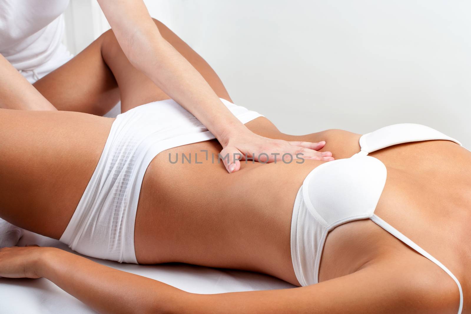 Close up of osteopath doing abdominal massage on woman.