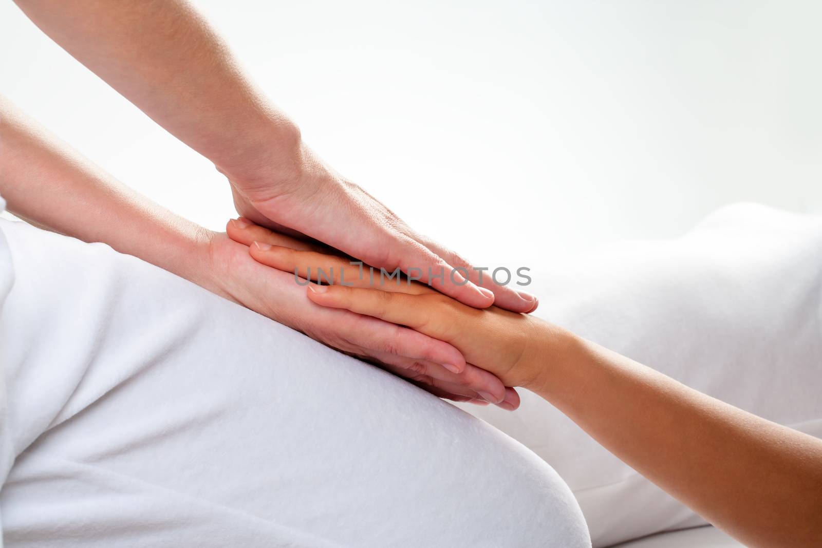 Close up of chiropractor doing reiki treatment on girls hand.