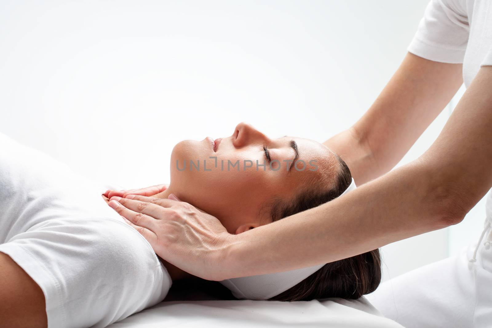 Close up portrait of young woman at reiki session.Therapist touching woman’s neck wit hands.