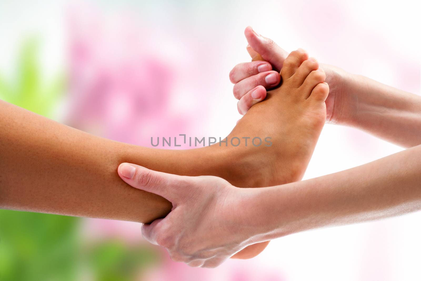 Extreme close up of therapist doing osteopathic massage on female foot. Colorful background.