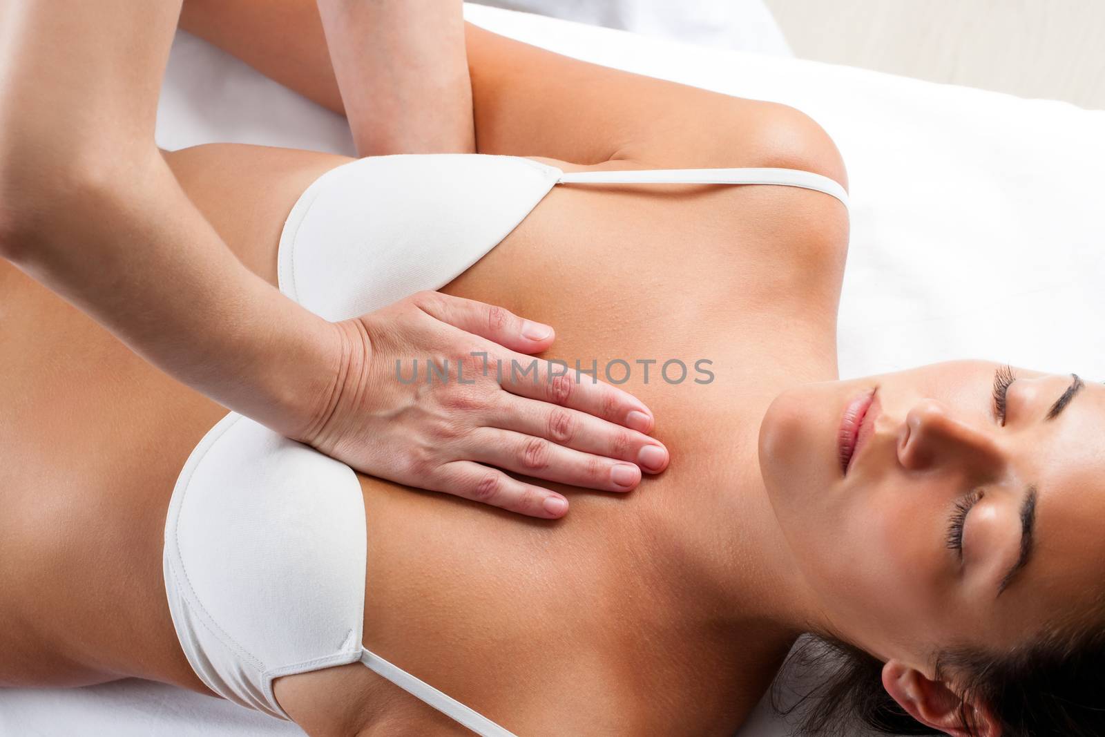 Close up of physiotherapist doing manipulative massage on young woman’s chest.