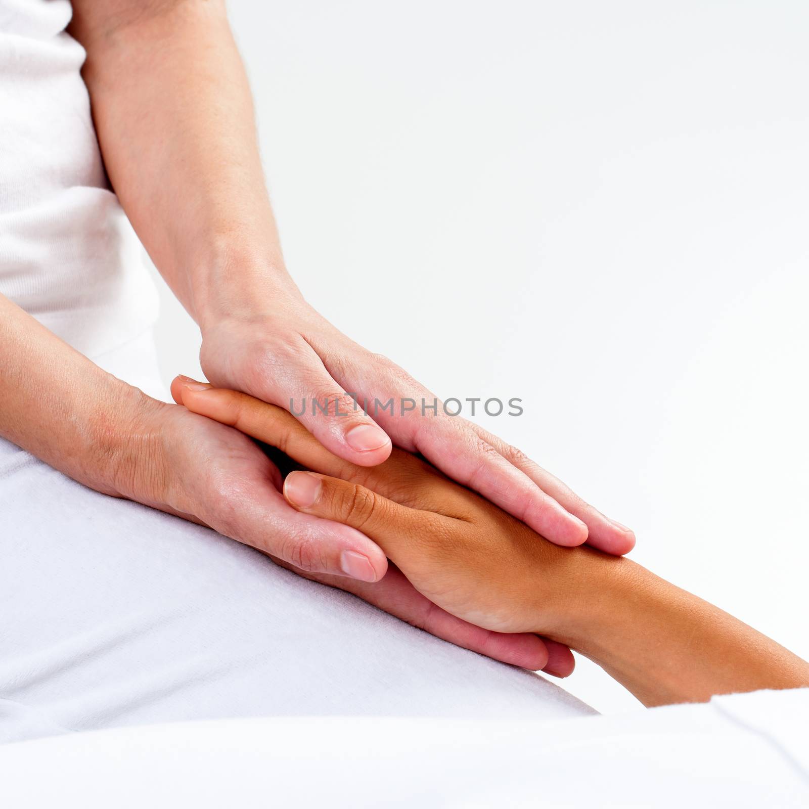 Macro close up of therapist hands holding woman’s hand.Healing treatment at reiki session.