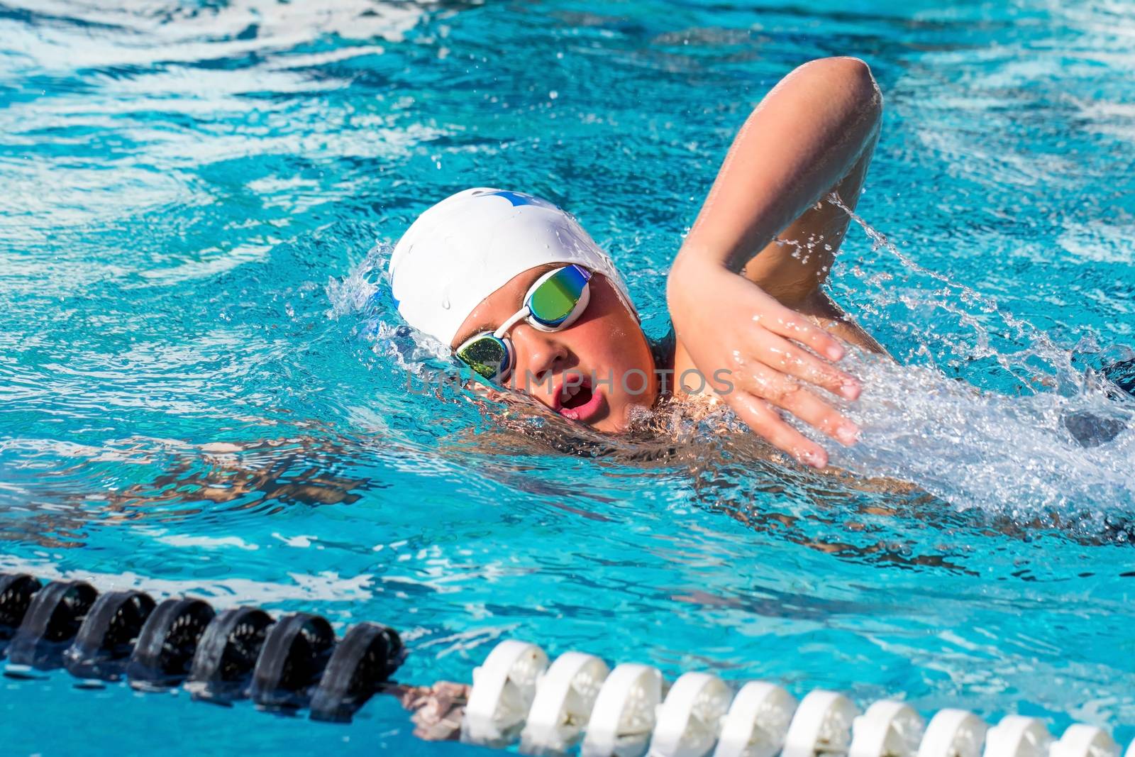Close up action shot of teen boy swimming freestyle at swimming practice.