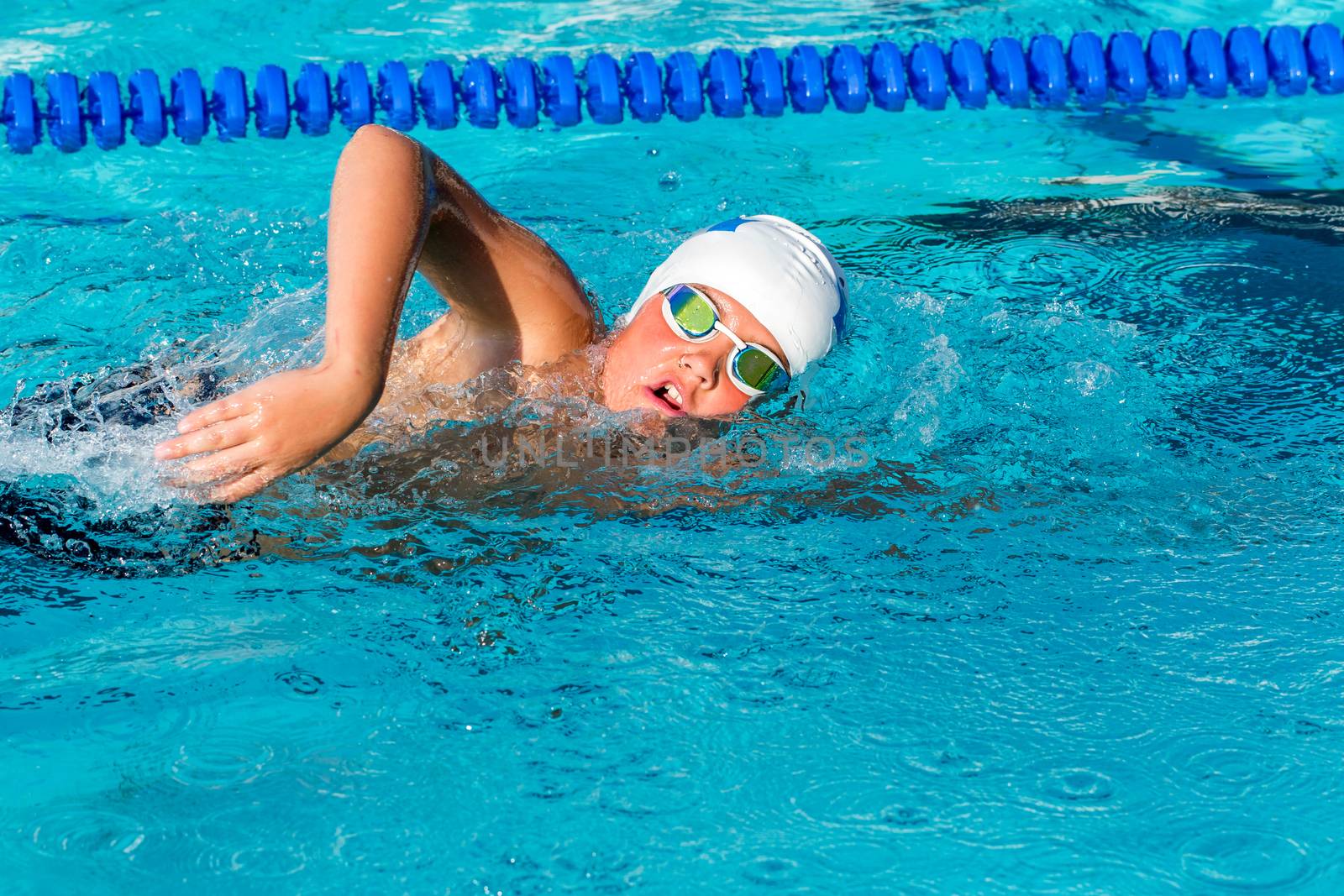 Close up action shot of teenager practicing freestyle in swimming pool.