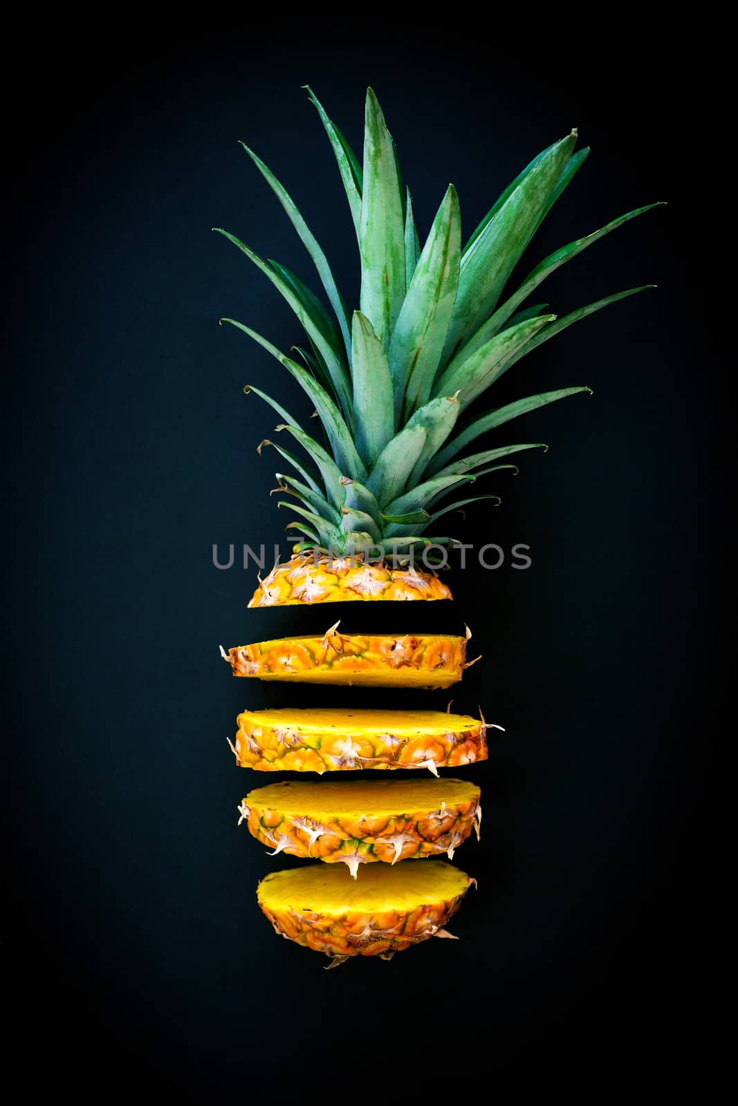 Sliced pineapple flying on dark background. Minimal food concept with summer fruits.