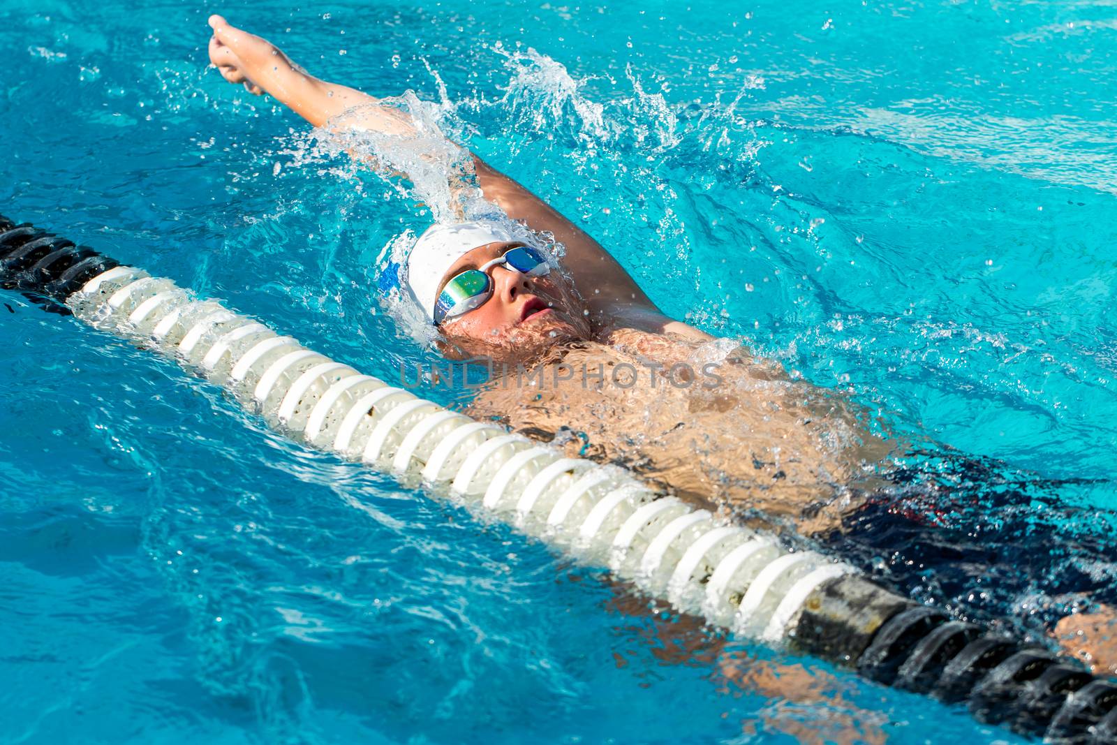 Teen backstroke swimmer in action. by karelnoppe