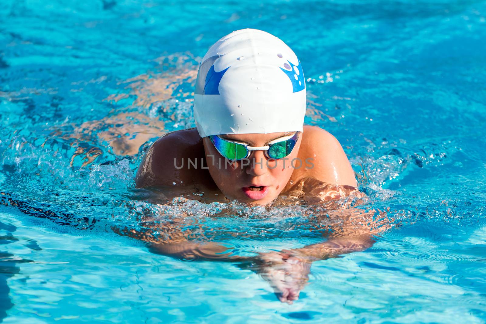 Close up action shot of young boy swimming breaststroke.