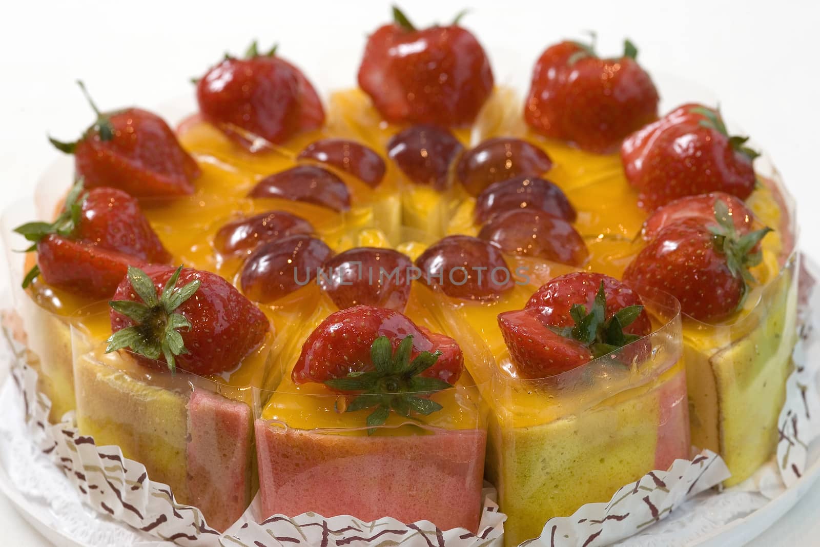 Fresh fruit cake with strawberries and plum sliced in pieces. Close up view.