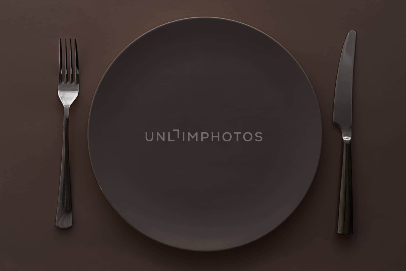 Empty plate and cutlery as mockup set on dark brown background, top tableware for chef table decor and menu branding design