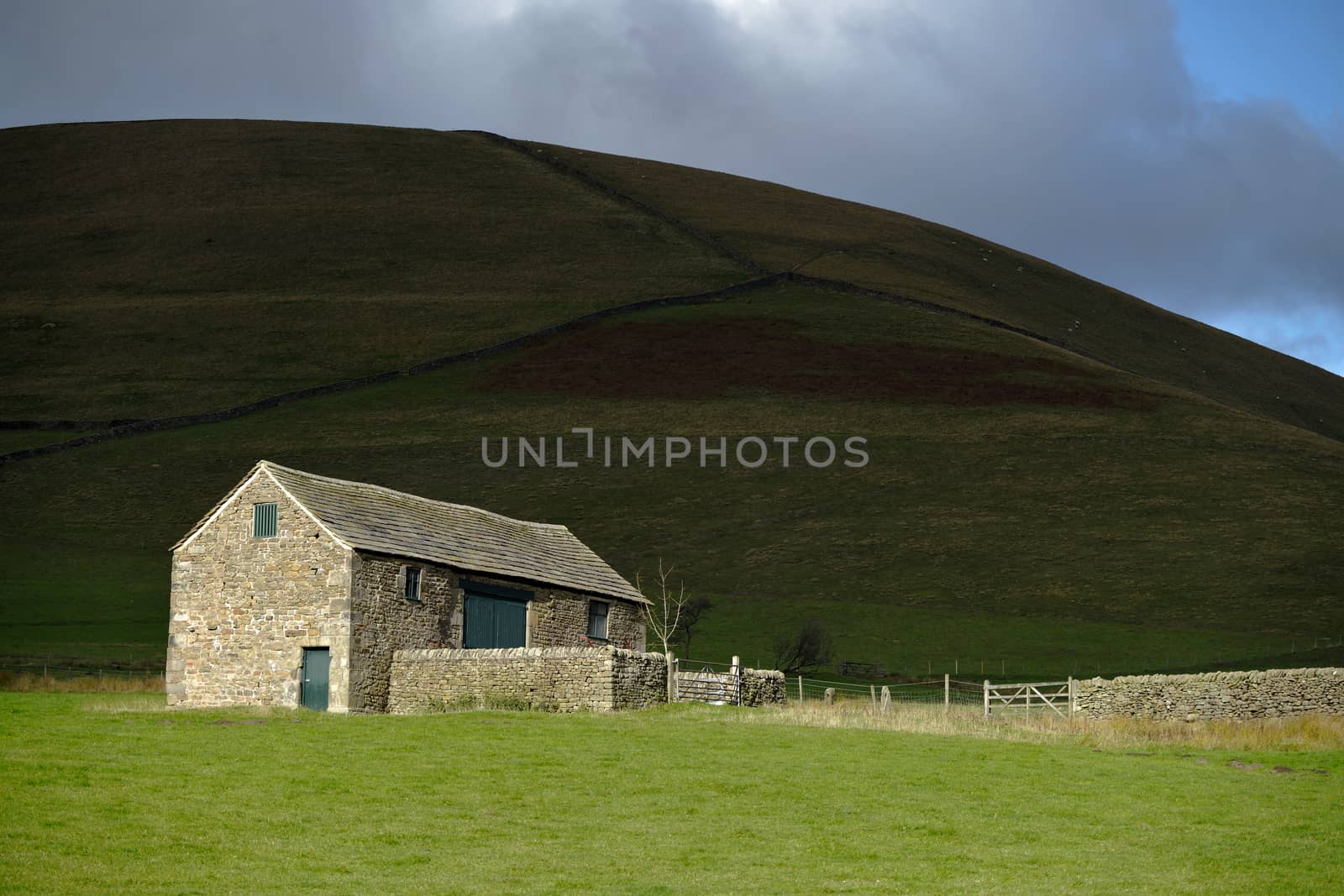 stone farm building in the peak district and bright sun.