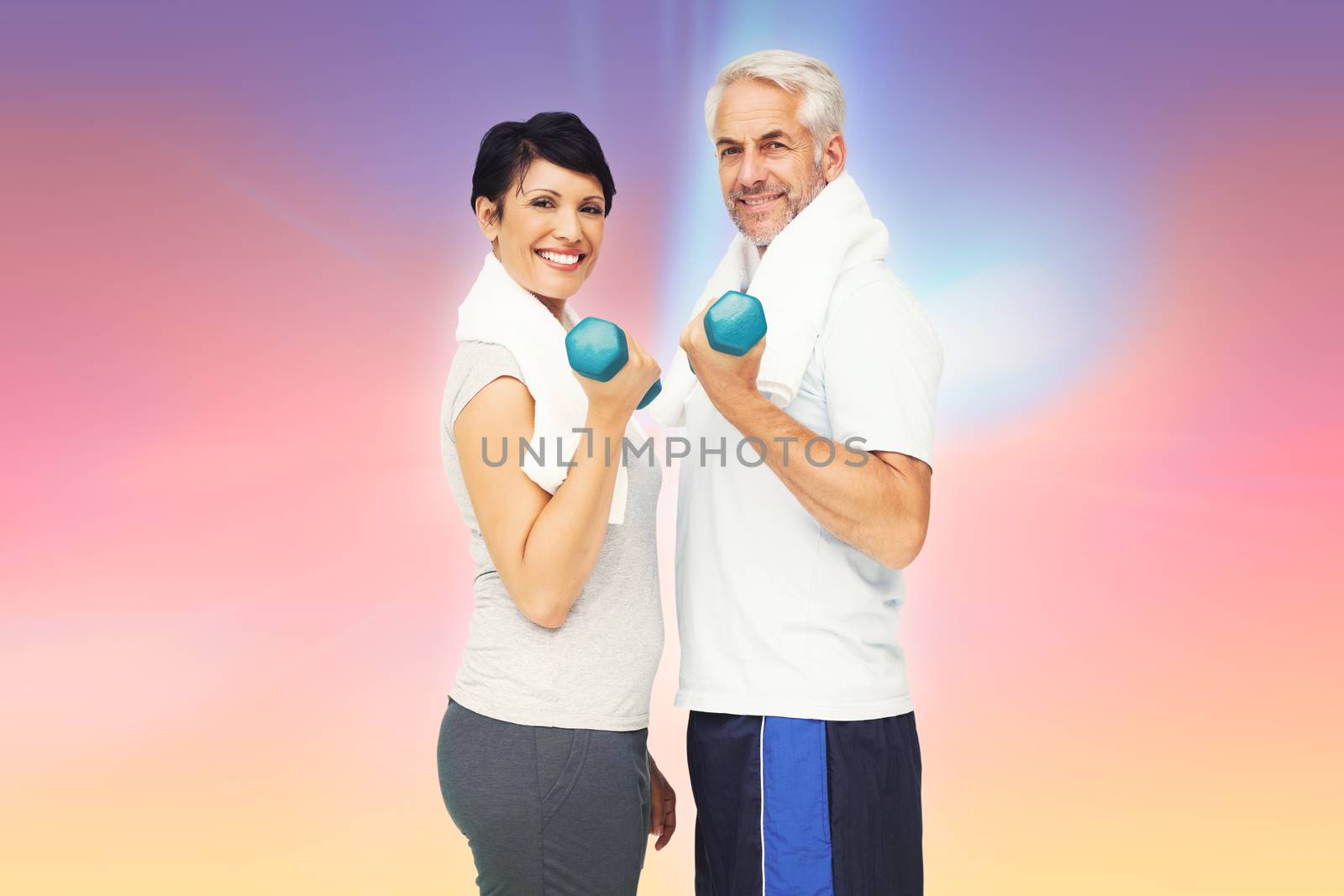 Portrait of a fit mature couple exercising with dumbbells against abstract background