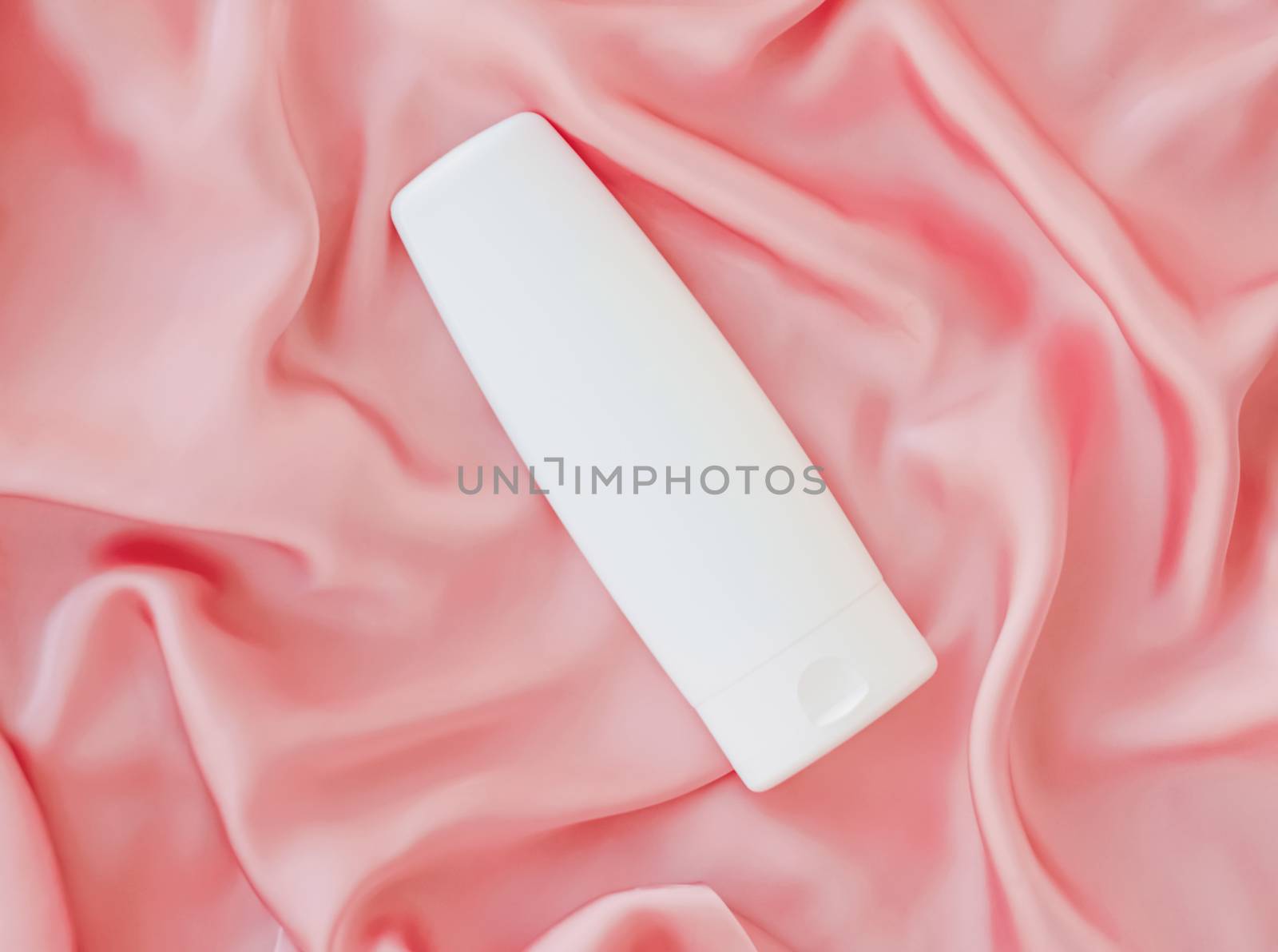 Blank label cosmetic container bottle as product mockup on pink silk background, hygiene and healthcare