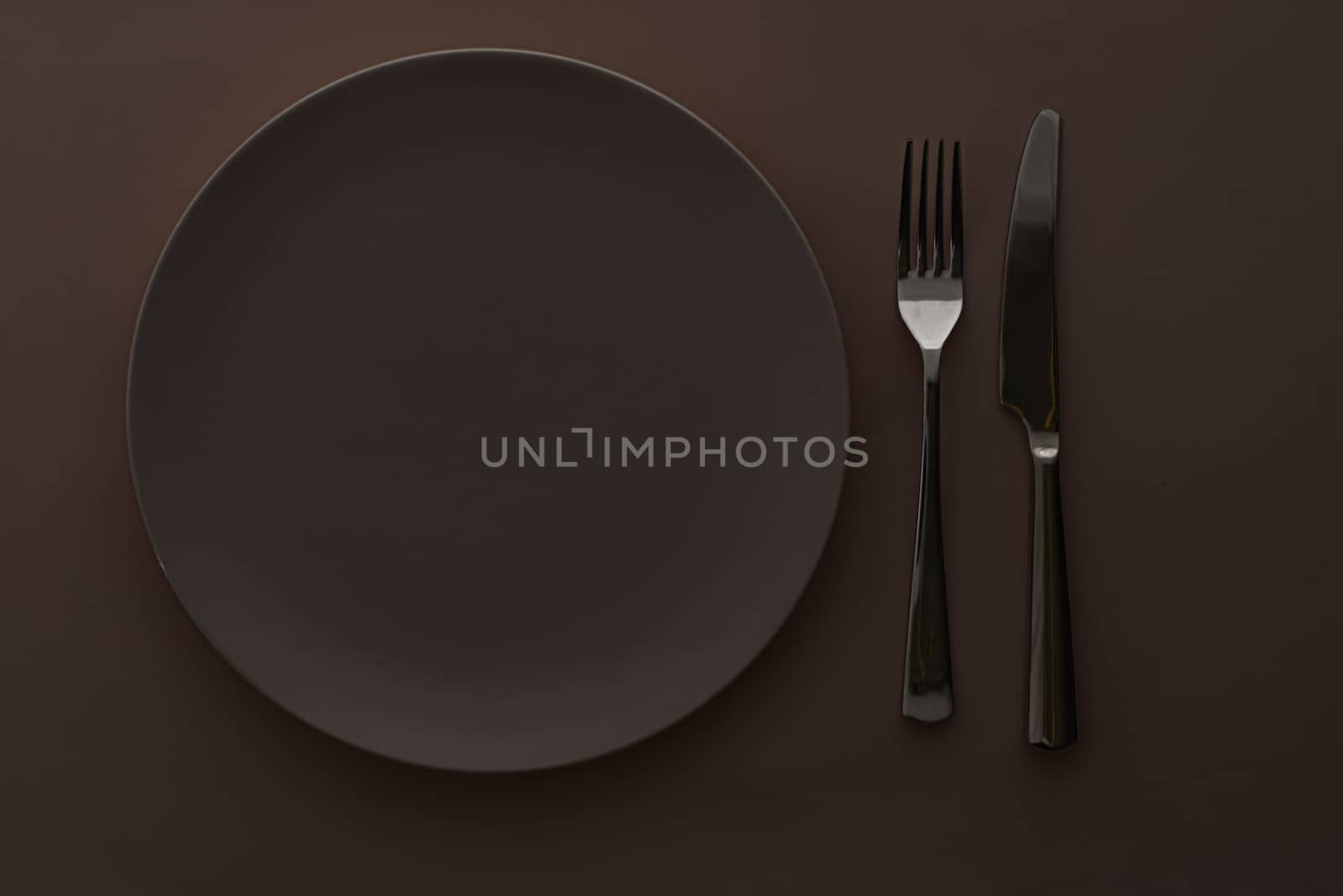Empty plate and cutlery as mockup set on dark brown background, top tableware for chef table decor and menu branding design
