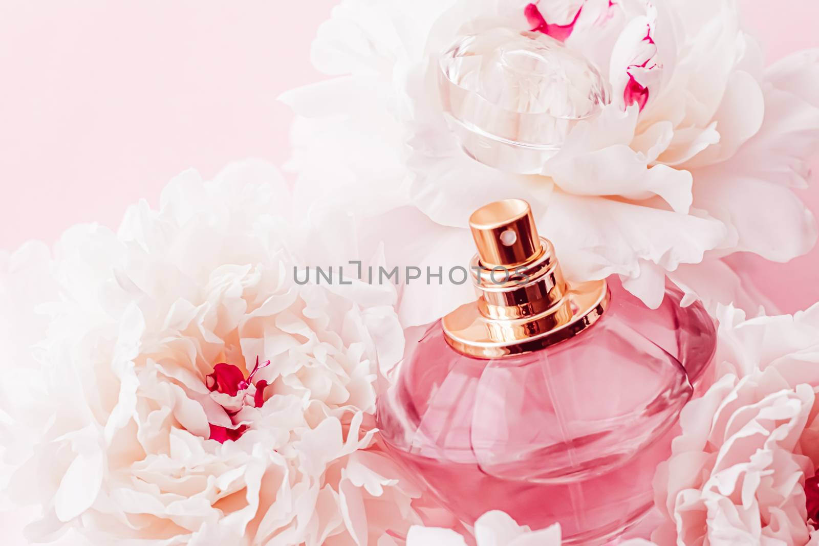 Luxe fragrance bottle as girly perfume product on background of peony flowers, parfum ad and beauty branding design