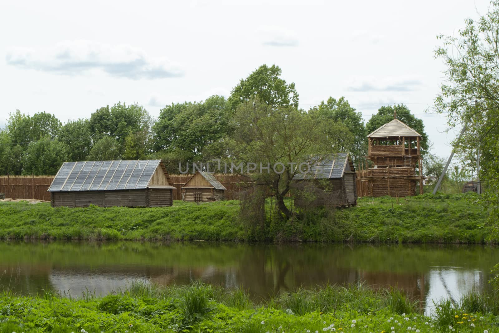 Ancient authentic rural wooden houses in Belarus, a cloudy day, calm river in landscape.