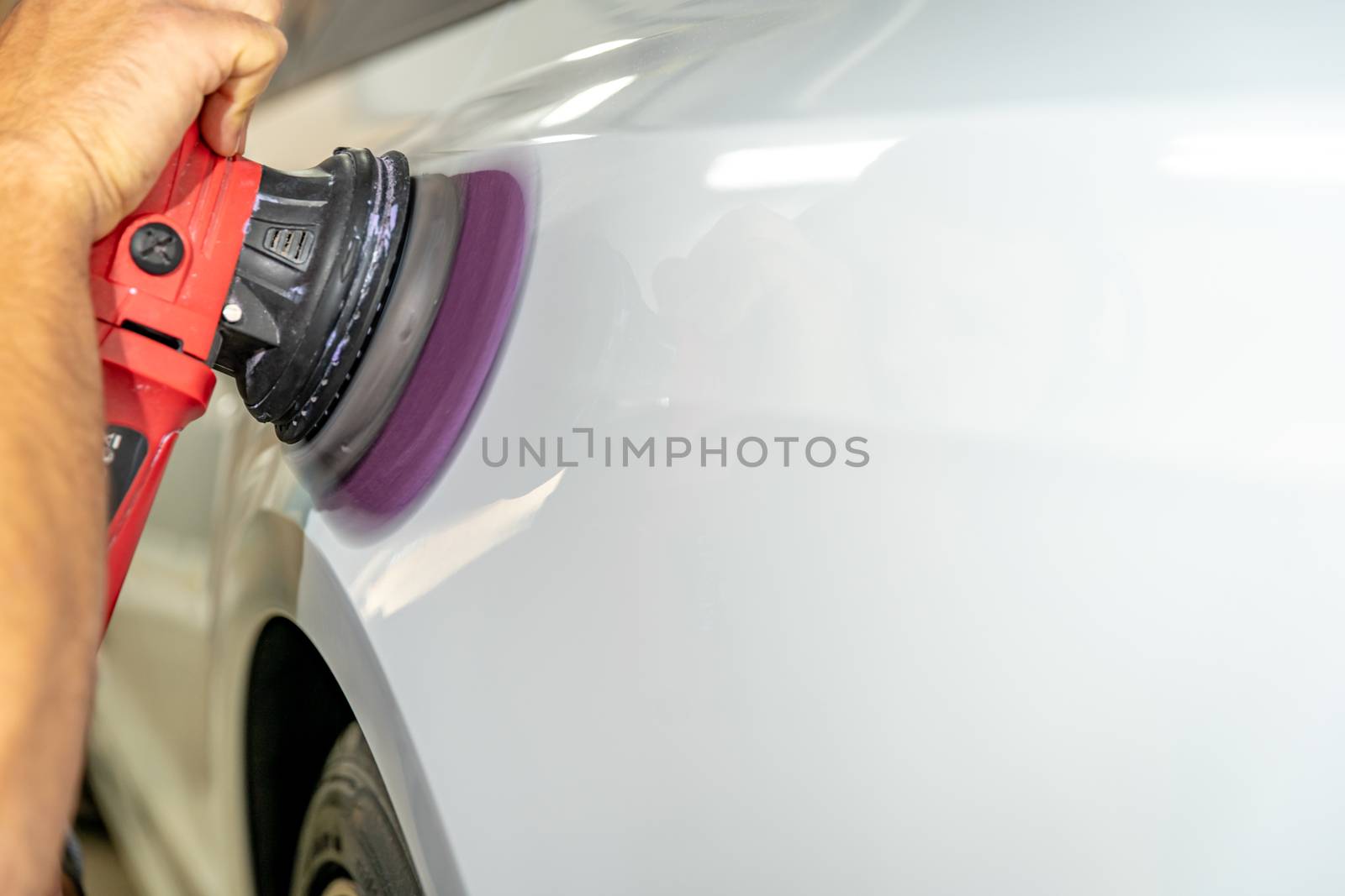 polishing the car body with a manual automatic grinder with wax and polishing paste by Edophoto