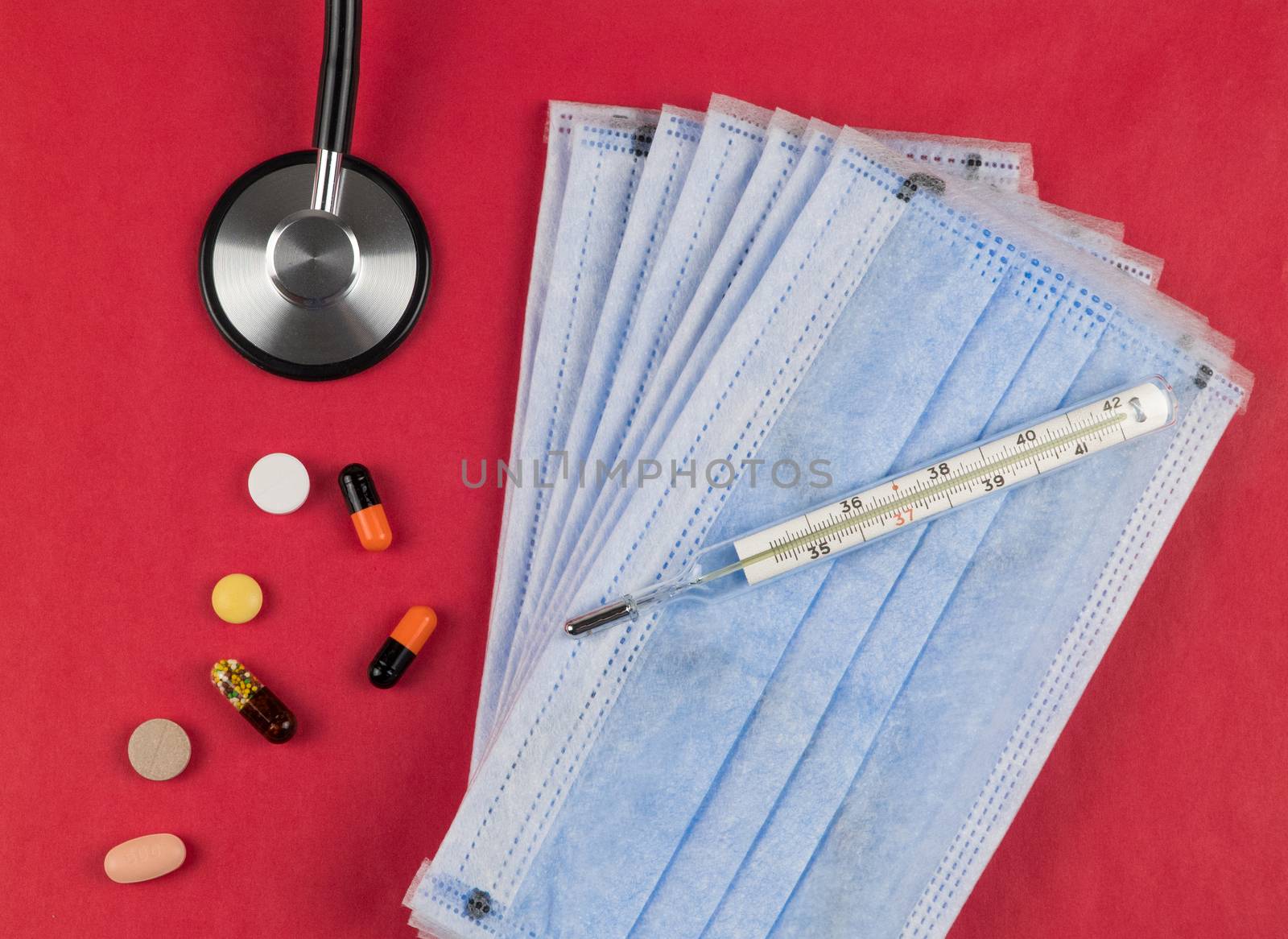 Medical protective masks on a red background with tablets, a thermometer and a stethoscope.. Coronavirus Protection Concept