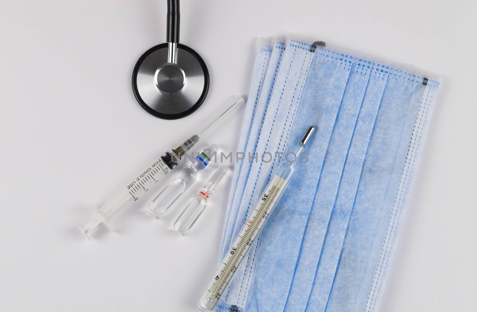 Medical protective masks on a white background with capsules, a thermometer and a stethoscope. Coronavirus Protection Concept