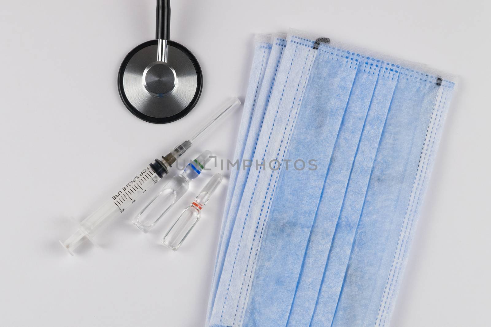 Medical protective masks on a white background with a stethoscope, a capsules and a syringe. Coronavirus Protection Concept