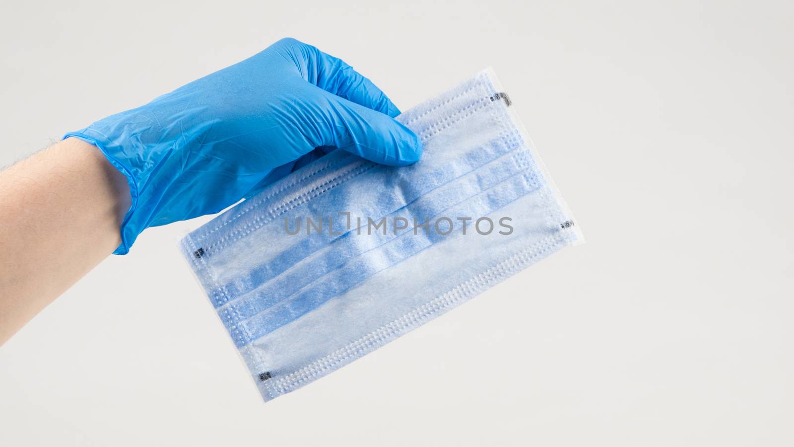 Hand holding a medical protective mask on a white background. Coronavirus Protection Concept