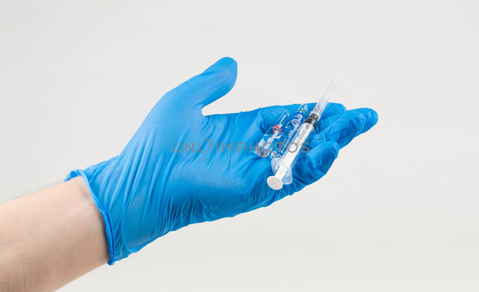 Hand in glove holds a syringe and a vaccine on a white background. Coronavirus Protection Concept