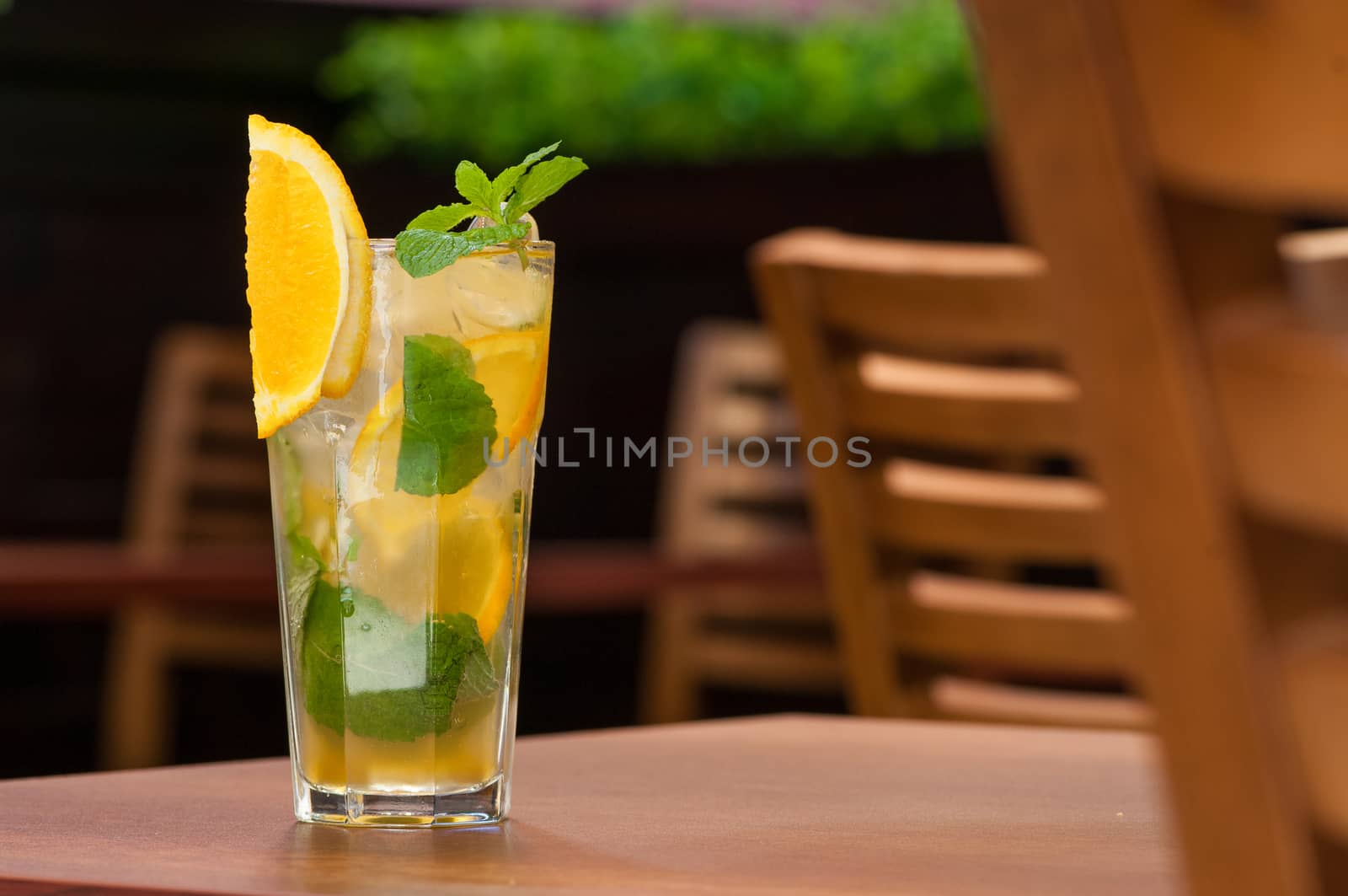 a cold drink with a yellow citrus on the table in a glass
