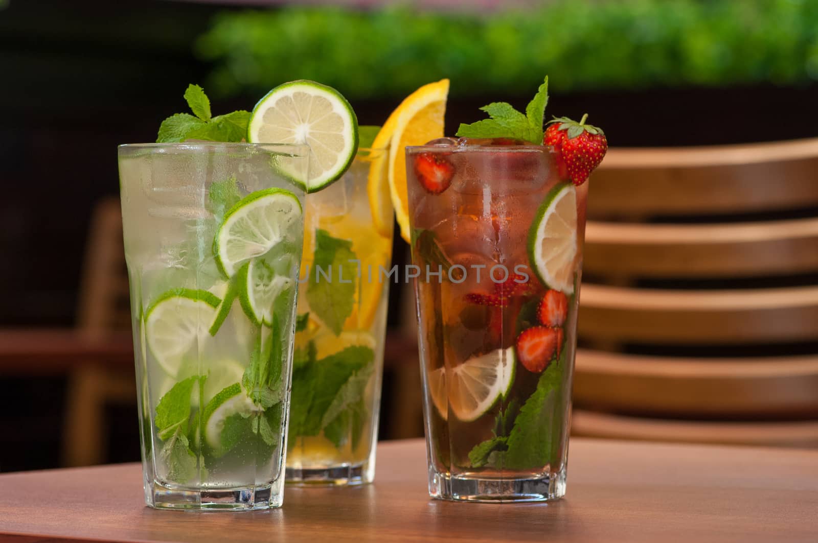 three cold drinks with citrus and strawberries in a glass on the table