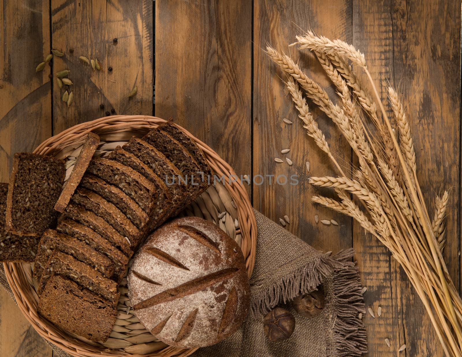 Sliced bread in a wicker tray with spikelets wooden surface with cloth