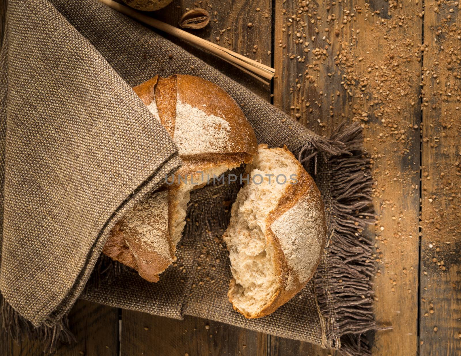 a broken loaf of bread on a cloth napkin and wooden boards with crumbs