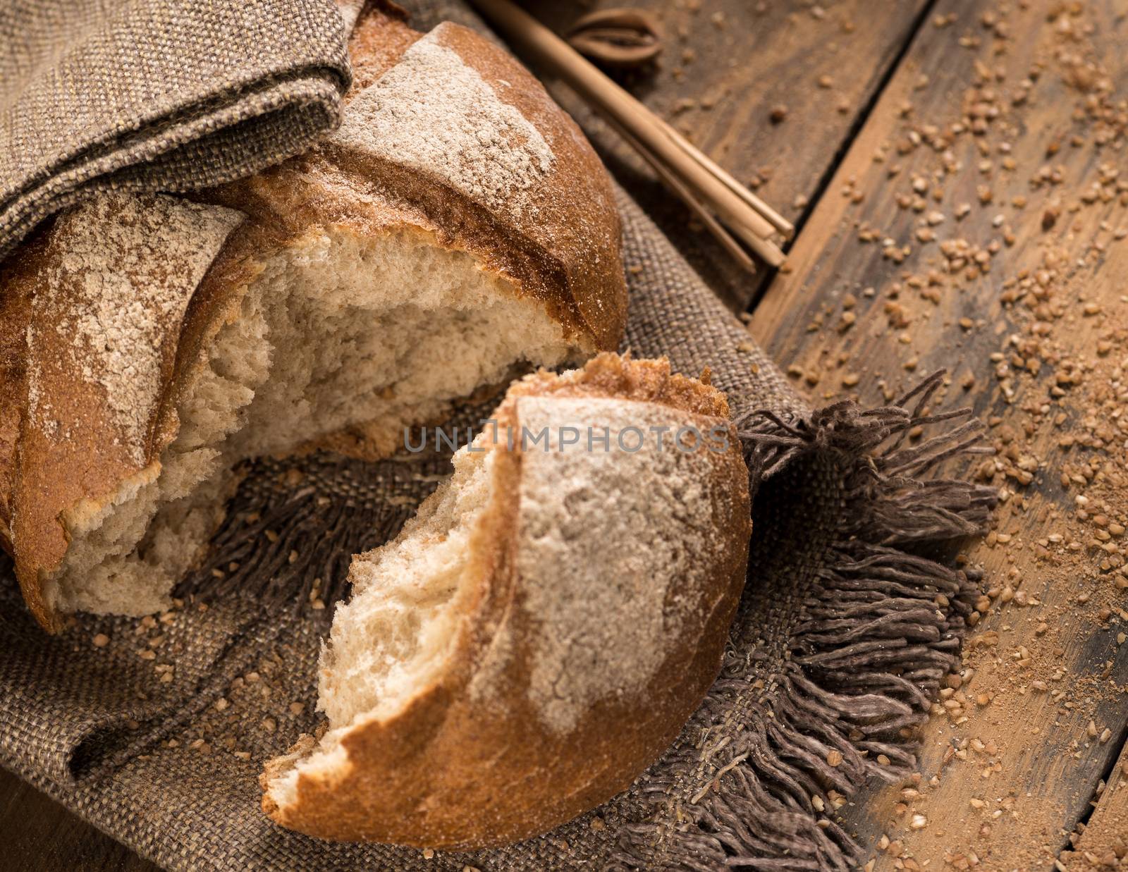 a broken loaf of bread on a cloth napkin and wooden boards with crumbs