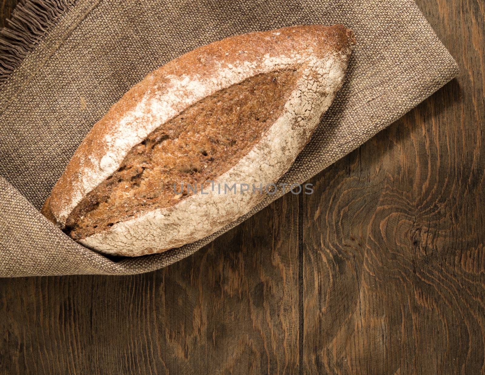 a loaf of bread on a cloth napkin and wooden boards, top view