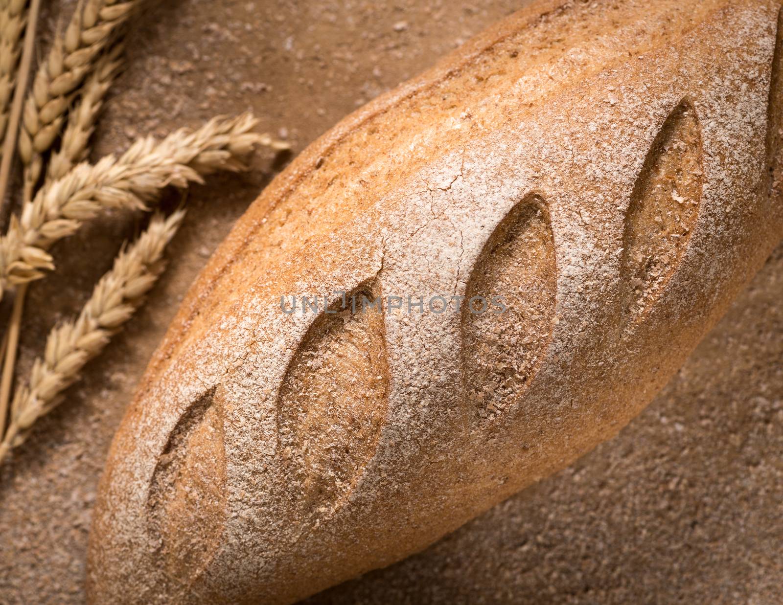 closeup of a loaf of bread with an spikelets of wheat and crumbs