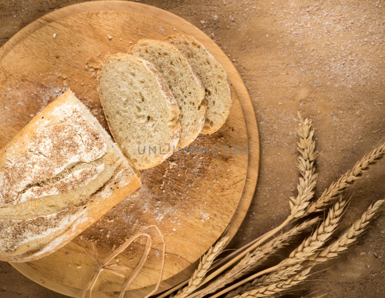 sliced bread on a round wooden tray with spikelets and crumbs