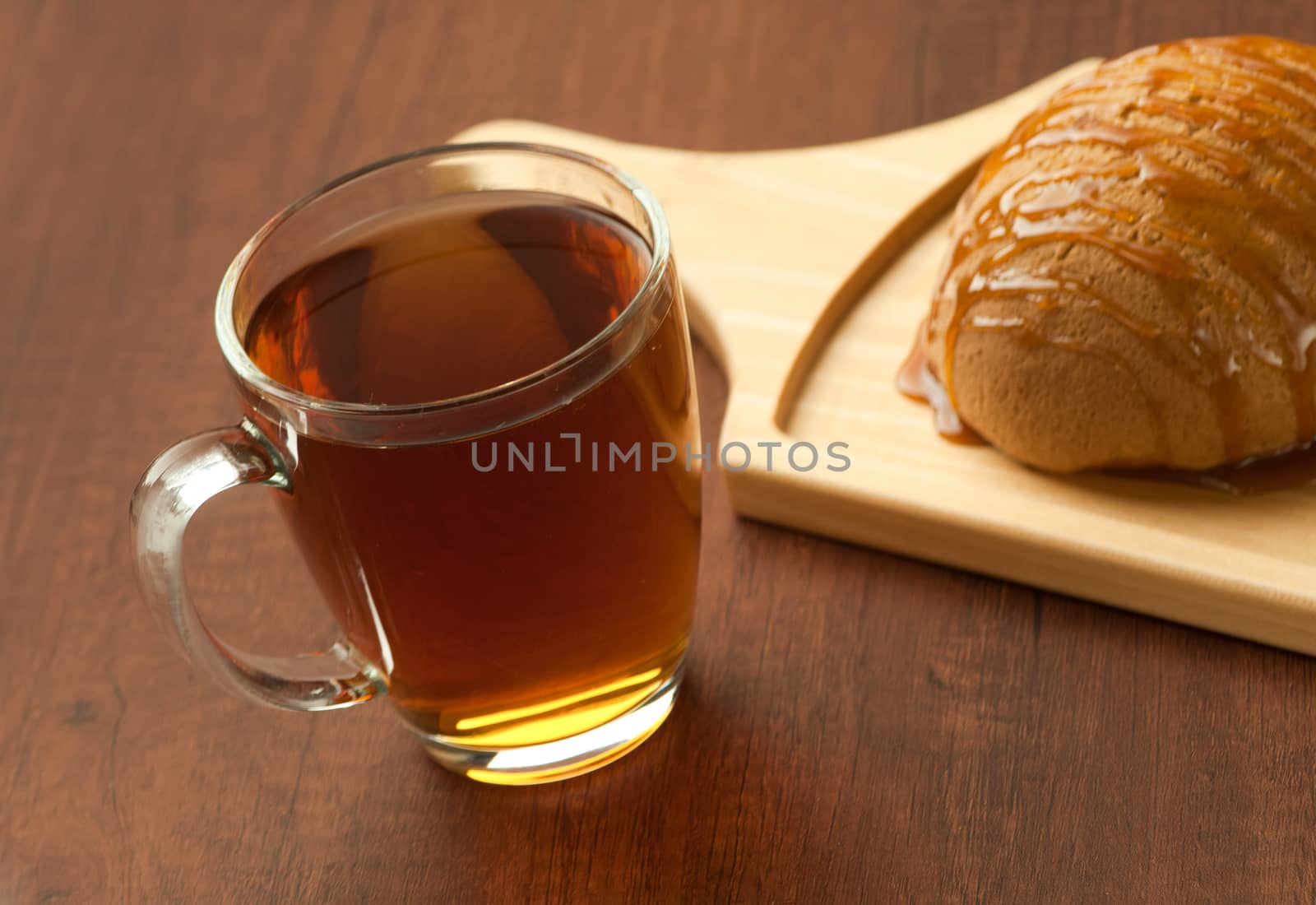 bread drizzled with honey on a wooden plate and a cup of black tea