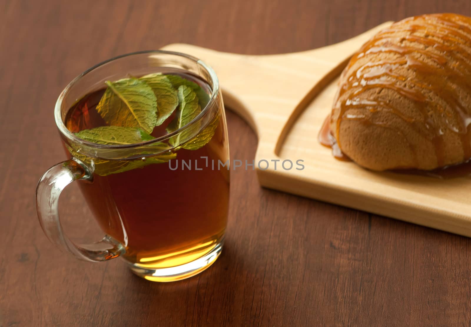 bread drizzled with honey on a wooden plate and a glass of black tea with leaf
