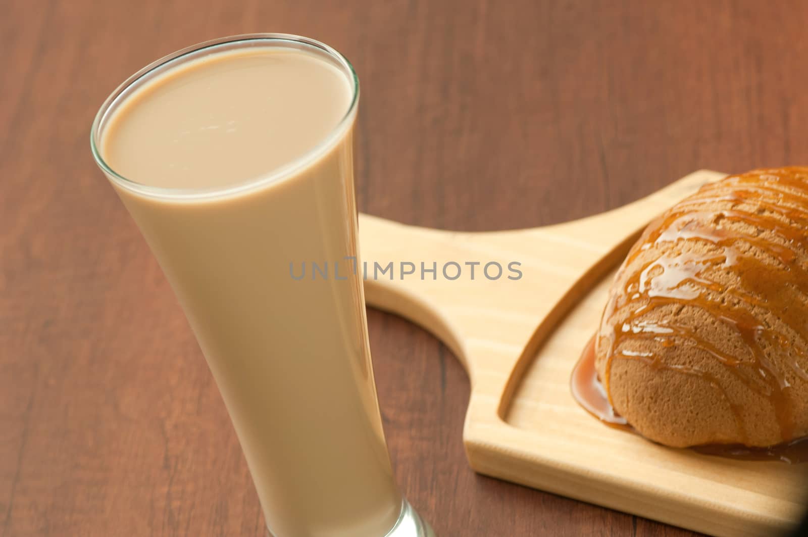 bread drizzled with honey on a wooden plate and a glass of milkshake