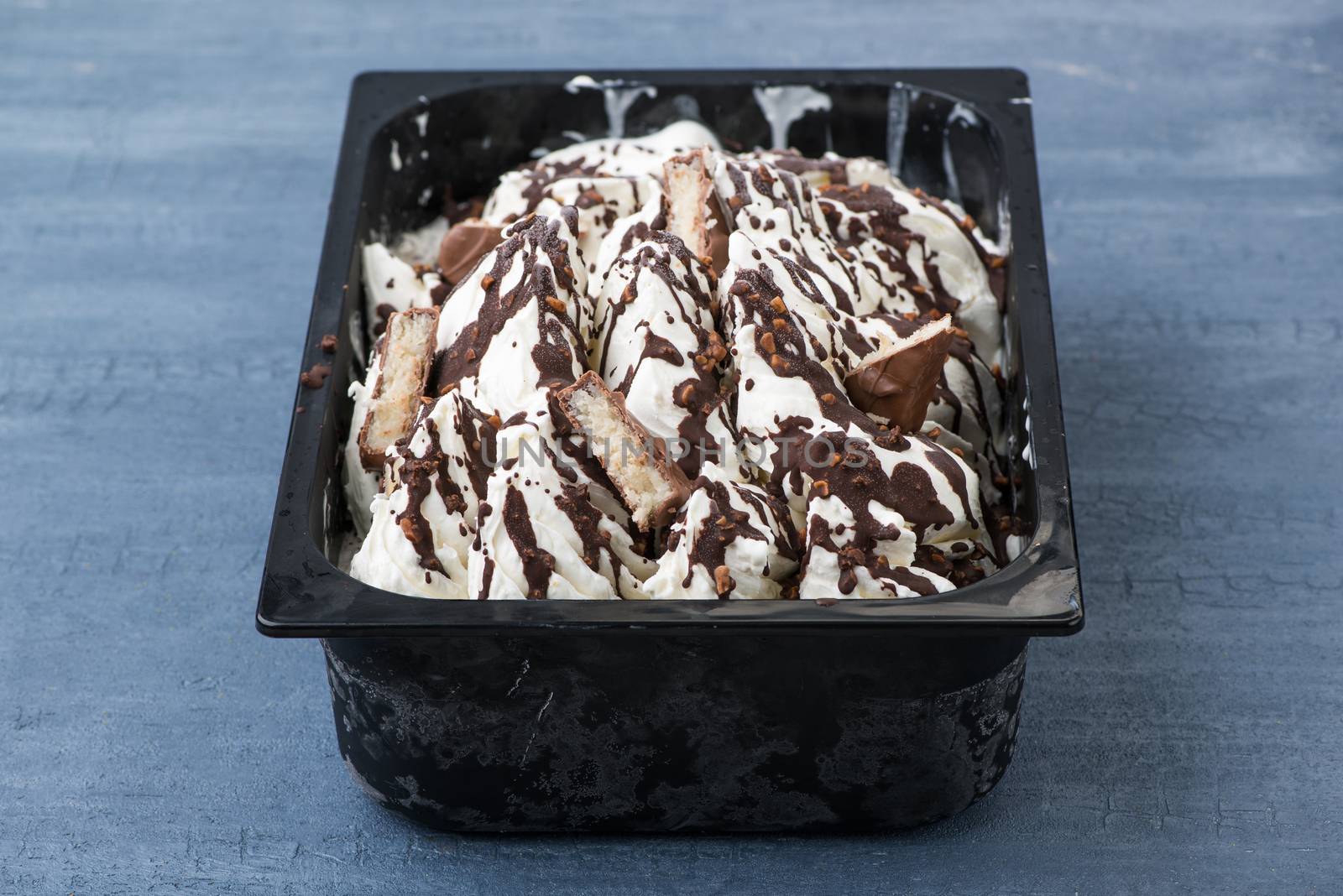 appetizing ice cream in a plastic container on a decorative blue background