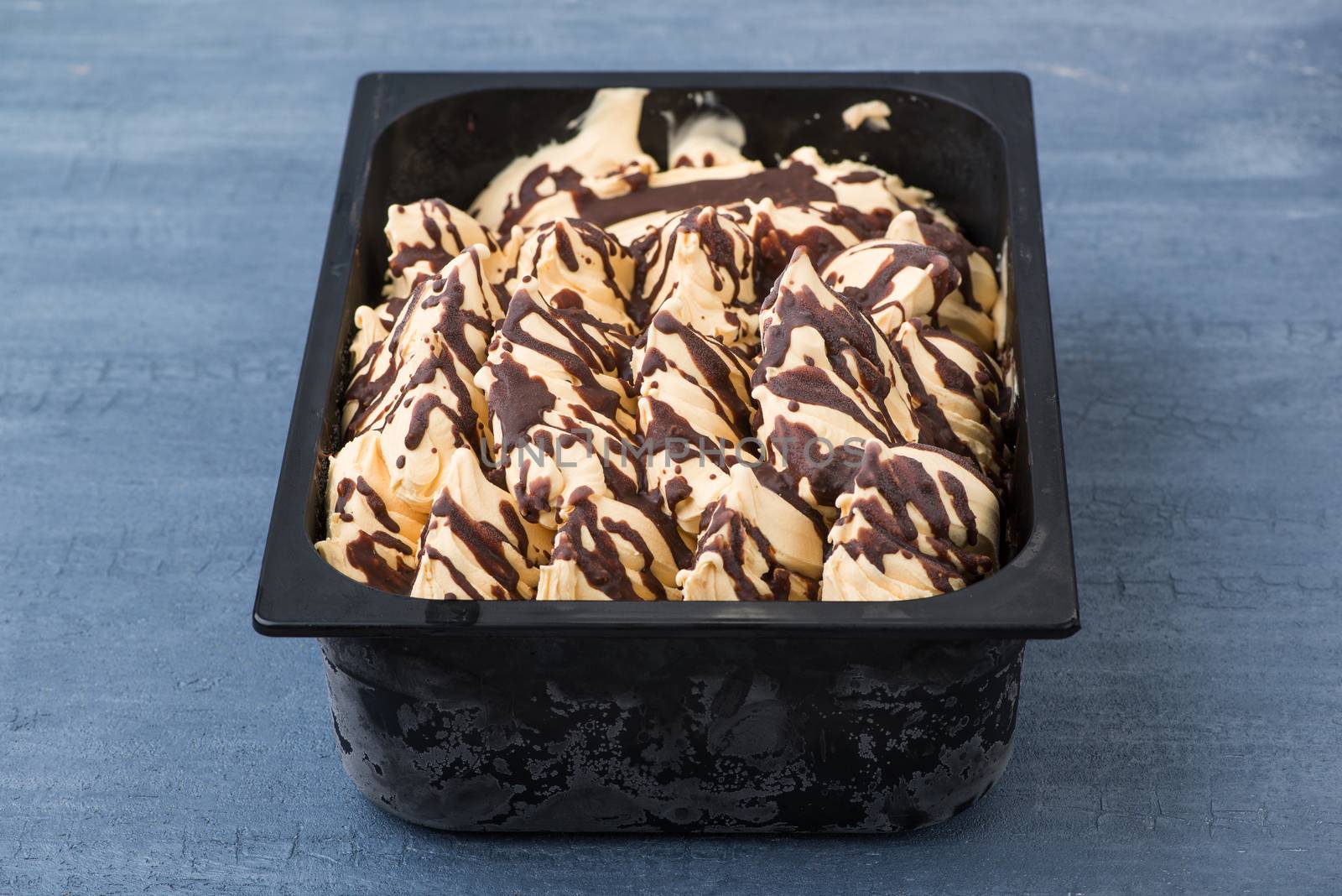 appetizing ice cream in a plastic container on a decorative blue background