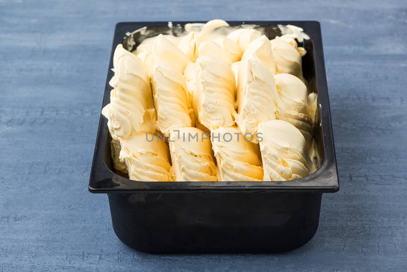 appetizing ice cream in a plastic container on a decorative blue background