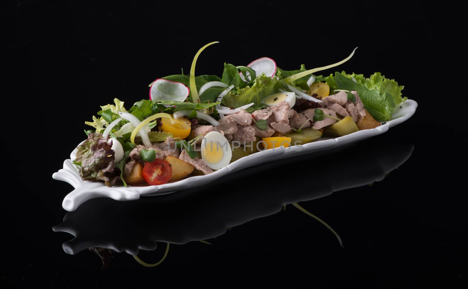 meat salad with eggs on a black background, isolated