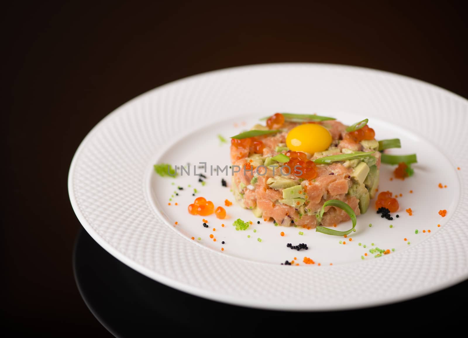 salad in a white plate on a black background