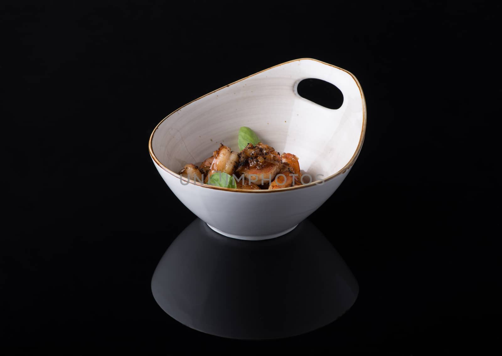 dish of meat in a bowl on a black background, isolated