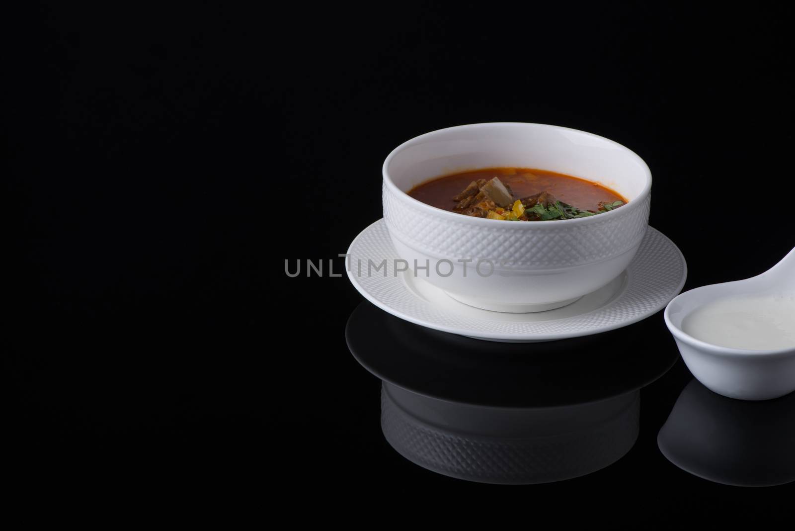 meat soup in a white bowl on a black background, isolated
