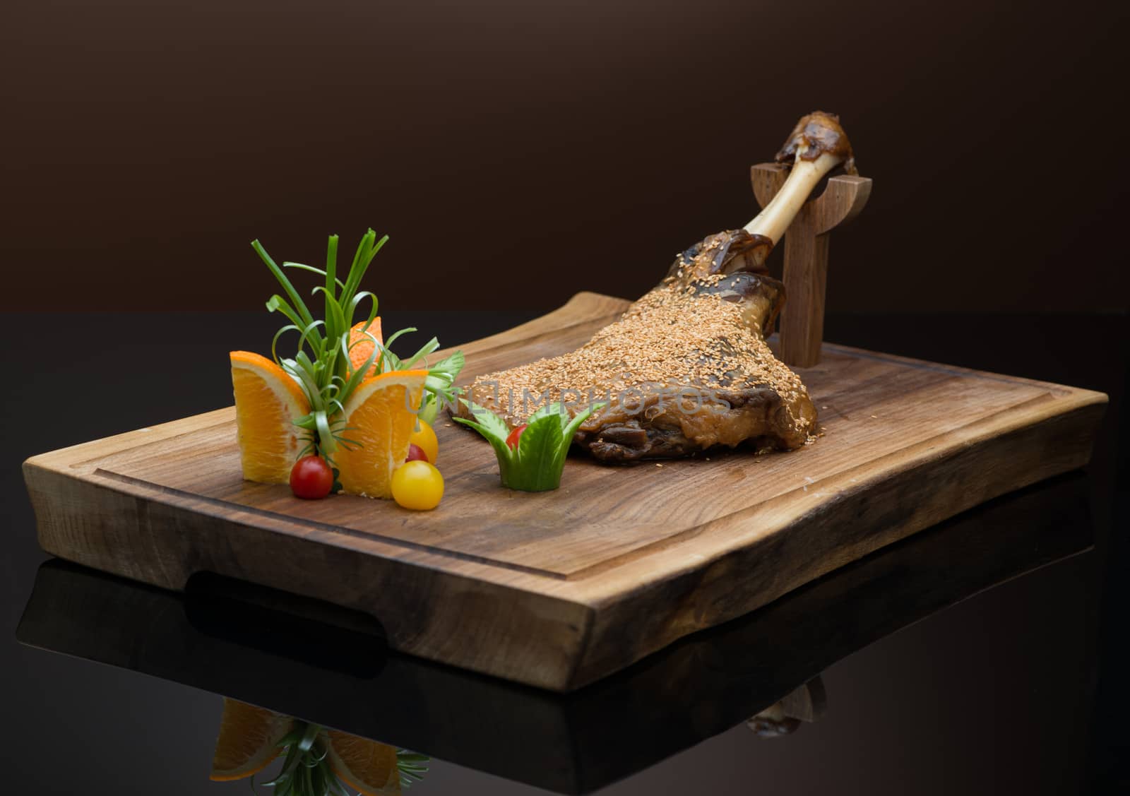 roasted meat with sesame seeds on a wooden tray, on a dark background